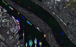 Satellite image showing a colorful overlay of a city and waterway, with various bright spots and lines representing different data points.