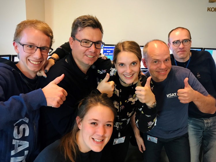 Group of six people smiling and giving thumbs up, with some wearing KSAT shirts.